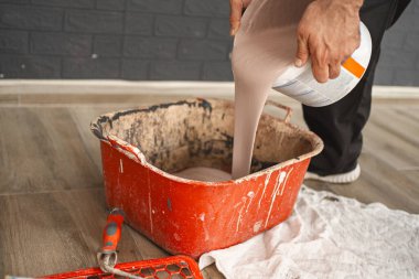 Boyanın döküldüğü ve boyanmaya hazır olduğu büyük kırmızı bir konteynırın yakın çekimi..