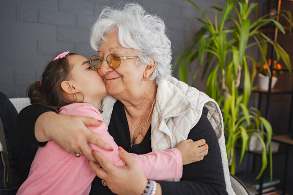 A loving embrace as a young girl kisses her grandmother on the cheek.
