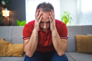 Evde tek başına oturan adam üzgün ve perişan görünüyor..