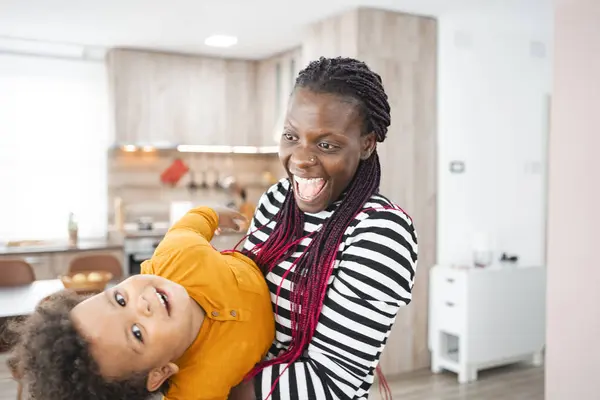 stock image A mother playfully lifts her laughing child in a bright kitchen.