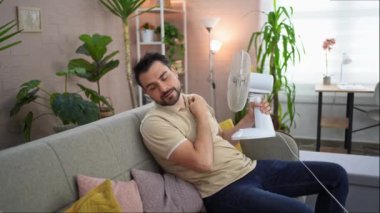 Bir adam kanepede dinlenir hayranlarının esintisiyle ferahlar..