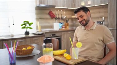 Bir adam sıcak bir mutfak ortamında narenciye içkisinin tadını çıkarır..