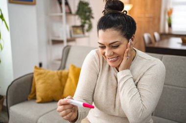 Woman feeling excited after doing a pregnancy test. clipart