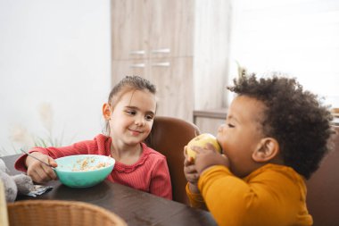 Kardeşler yemek masasında keyifli bir kahvaltı anı paylaşırlar..
