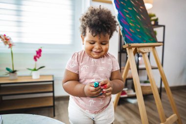 Genç bir çocuk, rahat evlerinde renkli resimler yaparak mutlu bir şekilde sanat yaratıyor..