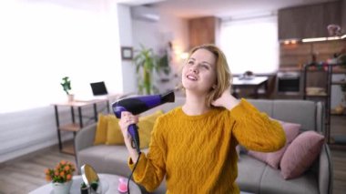 Bir kadın şarkı söyleyip saçlarını içeride tararken neşeli bir an..