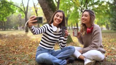 Arkadaşlar güzel bir parkta kahvelerini yudumlarken neşeli anları yakalar..