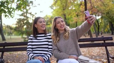 Arkadaşlar neşe dolu sonbahar yeşilliklerinde selfie çekerken kahkahalarını paylaşırlar..