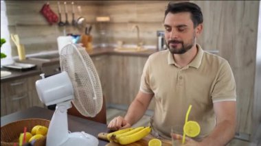 Bir adam, neşeli mutfağında dinlenirken soğuk bir içkiden zevk alır..