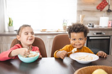 Mutfak masasında iki çocuk kahvaltıyı mutlulukla paylaşıyor..