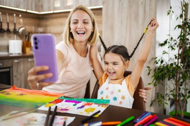 Neşeli bir anne ve kızı evlerinde güzel sanatlar yaratırken birlikte hoş bir an yakalıyorlar.