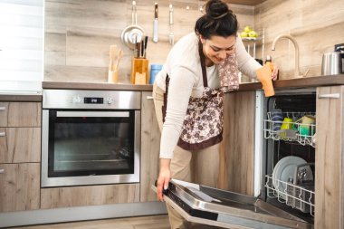 Mutfakta bulaşık makinesini dolduran kadın..