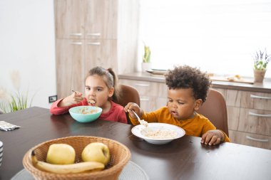 Çocuklar mutfak masasında meyveli kahvaltı yapıyorlar..