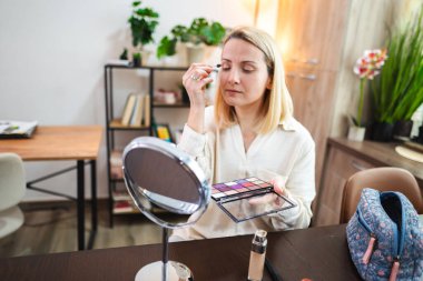 Bir kadın renkli bir paletle makyaj uygulamasına odaklanır..