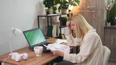 Huzurlu bir ev ofisinde, aşırı çalışan bir birey stresle savaşırken evrak işlerini düşünür. Yumuşak ışıklandırma ve yeşillik, yaklaşan teslim tarihlerinin gerginliğiyle bir tezat oluşturuyor.