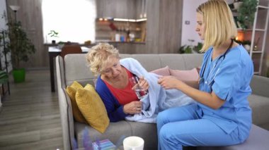 Şefkatli bir sağlık uzmanı, evde yaşlı bir kadına yardım eder. Bakım ve destek sağlarken aynı zamanda rahatlık ve su ihtiyacını karşılar..