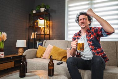 Genç adam televizyonda maç izleyip birayla kutluyor.