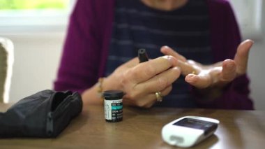 Sıcak, davetkar bir yerde, bir kişi kan şekeri seviyesini bir metre kullanarak ölçer. Sahne, günlük hayatta kişisel bakım ve sağlık yönetiminin önemini yansıtıyor..