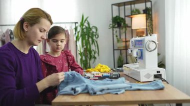 Bir anne kızına renkli kumaşlarla dikiş dikmeyi öğretir..