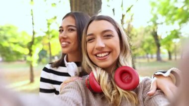 İki arkadaş parkta güneşli bir günün tadını çıkarıyorlar, gülümsüyorlar ve birlikte anılar yaratıyorlar..