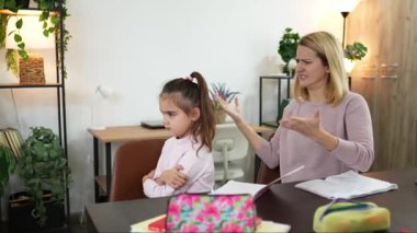 Çağdaş bir ev ofisinde, bir anne duygularını ifade ederken kızı kollarını kavuşturup bir anlık iletişim ve duygu gösterisi yapar..