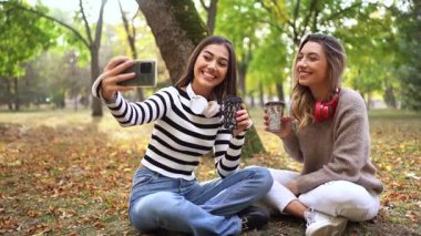 Arkadaşlar güzel bir parkta kahvelerini yudumlarken neşeli anları yakalar..