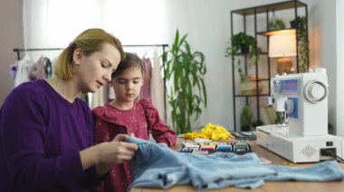 Bir anne, kızına rahat bir çalışma alanında dikiş eğitimi verir..