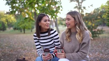 Arkadaşlar sıcak içecekleri paylaşırken aynı zamanda canlı sonbahar atmosferinin tadını çıkarırlar..