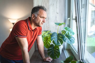 Pencerenin yanında duran adam üzgün ve perişan görünüyor..