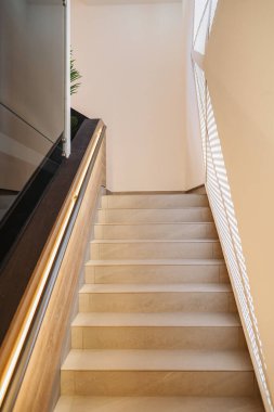 Birinci kattan bir binanın ikinci katına çıkan bir merdiven seti. Merdivenler ahşaptan yapılmış ve güvenlik için korkulukları var. Tasarım basit ve işlevseldir.