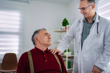 Bir doktor klinikte yaşlı bir hastayla sıcak bir şekilde iletişim kurar..