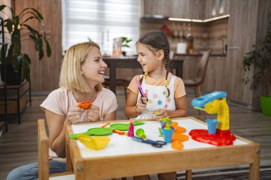 Bir anne ve kızı, rahat bir mutfak masasında canlı bir modelleme kiliyle yaratıcı bir oyun seansına giriyorlar..