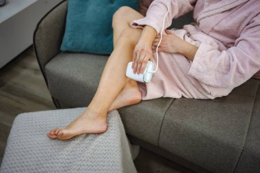 Evde taşınabilir lazer temizleme cihazı kullanan bir kadın.