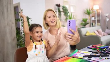 Rahat ve hareketli bir evde, bir anne ve kızı yaratıcılıklarını kutluyor, gülümsüyor ve çekici bir şekilde rengarenk sanat eserlerini sergiliyorlar ve birbirlerine eşlik etmekten zevk alıyorlar..