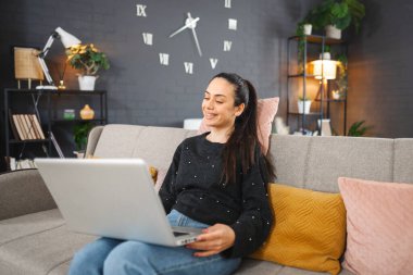 Genç gülümseyen kız dizüstü bilgisayar kullanmaktan hoşlanıyor.