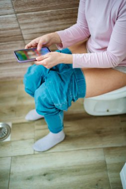 Akıllı telefonu karıştırırken banyoda rahatlatıcı bir anın tadını çıkarıyorum..