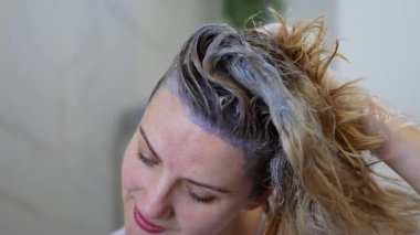 Bir kadın rahat bir atmosferin tadını çıkarırken canlı saç boyası sürer..