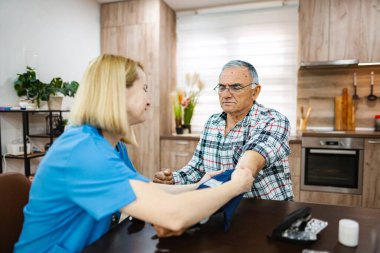 Hemşire evde kıdemli bir hastanın hayati belirtilerini kontrol ediyor..