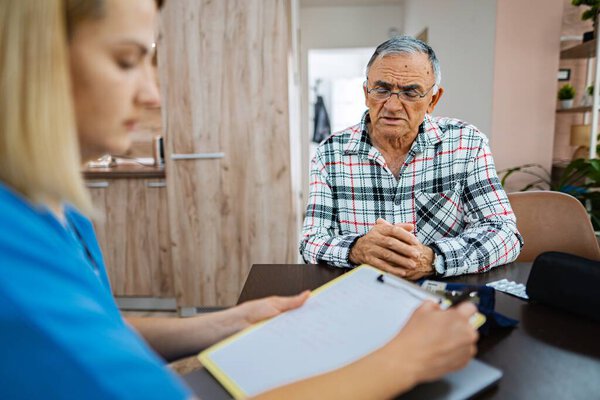 Старший джентльмен обсуждает свое здоровье с сиделкой.