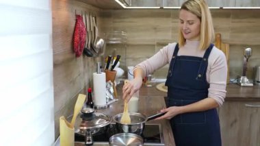 Neşeli bir birey sobanın tepesinde bir demlik karıştırıyor, mutfak malzemeleriyle dolu şık bir mutfakta yemek pişirme sanatını kucaklıyor. Atmosfer sıcaklık yayıyor..