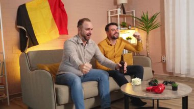 İki arkadaş maç izlerken tutkuyla içki içerek kutlama yapıyor..