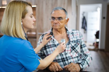 Tıbbi uzman yaşlı bir adamın sağlığını dikkatlice kontrol eder..