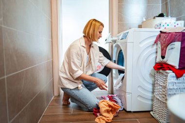 Bir kadın modern bir çamaşırhanede kıyafet düzenliyor..