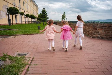 Tarihi kalenin yakınlarında üç kız el ele dolaşıyor..