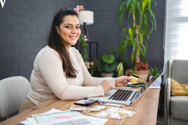 Gülümseyen kadın evde bilgisayardan alışveriş yapıyor..