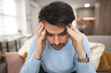 Bir adam kanepeye oturur, elleri bariz bir sıkıntı ya da hüsran içinde kafasına yapışır. Düşüncelere dalmış ya da duygusal bir karmaşa yaşıyor..