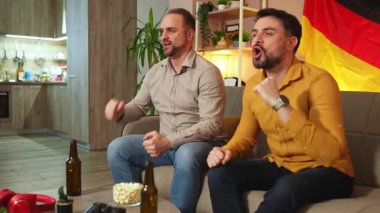 Arkadaşlar birlikte atıştırmalık ve içeceklerin tadını çıkarırken tutkuyla tezahürat yaparlar..