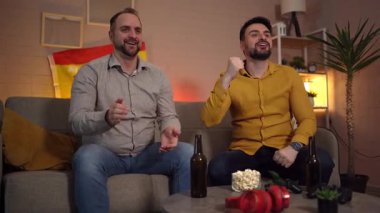 İki arkadaş tezahürat yapıp zaferi kutlarken abur cubur ve içkinin tadını çıkarıyor..