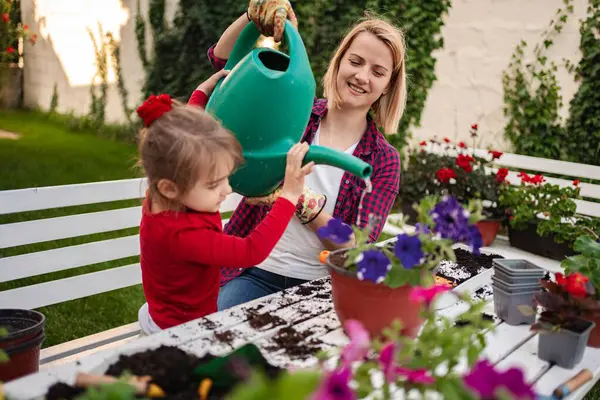 Bir çocuk gülümseyen bir yetişkinin yanında neşeyle çiçek salıyor..