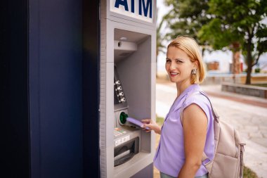 Yunanistan 'da güneşli bir günde ATM kullanan bir kadın.